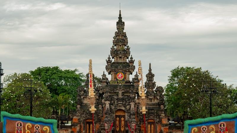 Gerbang megah Pusat Seni Denpasar dengan latar pertunjukan budaya, menggambarkan kekayaan seni dan tradisi Bali.