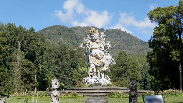 Patung di Kebun Raya Bedugul dengan latar belakang pegunungan hijau. Panduan Wisata Bali