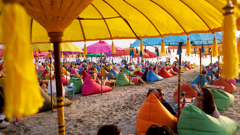 Wisatawan menikmati suasana santai di La-Planca Pantai Seminyak dengan bean bags berwarna-warni, salah satu dari 25 tempat wisata terbaik di Bali.