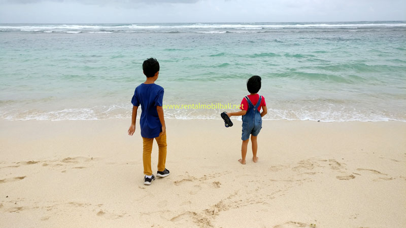 Dua anak asyik bermain pasir putih di Pantai Melasti, Ungasan, Bali.