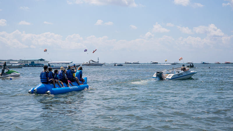 Keluarga dan teman menikmati kegembiraan banana boat di laut Bali.