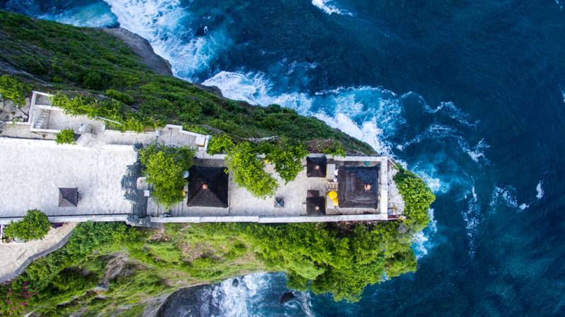 Pemandangan Pura Luhur Uluwatu di atas tebing dengan panorama Samudra Hindia di Bali