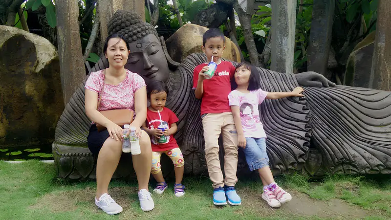 Momen keluarga di Big Garden Corner Sanur dengan patung Buddha sebagai latar belakang