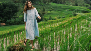 Wisatawan wanita berjalan di tengah sawah terasering Jatiluwih yang hijau dan subur