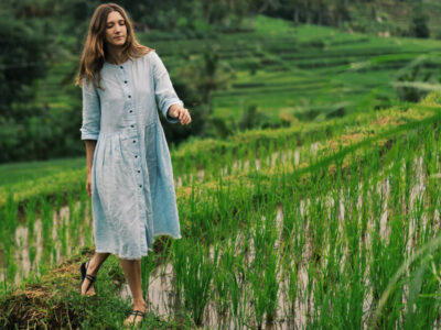 Wisatawan wanita berjalan di tengah sawah terasering Jatiluwih yang hijau dan subur