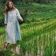 Wisatawan wanita berjalan di tengah sawah terasering Jatiluwih yang hijau dan subur