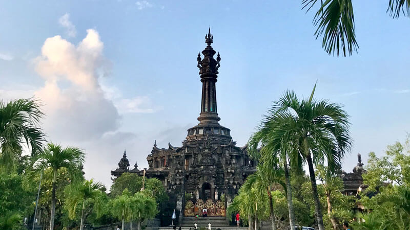 Monumen Bajra Sandhi yang megah berdiri di tengah taman hijau dengan langit biru di Denpasar, Bali.