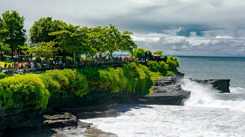 Pemandangan Pura Tanah Lot di Bali dengan deburan ombak di tebing