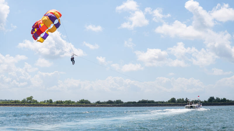 Wisatawan menikmati parasailing di Pantai Tanjung Benoa, Bali