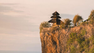 Pura Luhur Uluwatu yang megah berdiri di atas tebing tinggi dengan latar belakang langit senja di Bali.