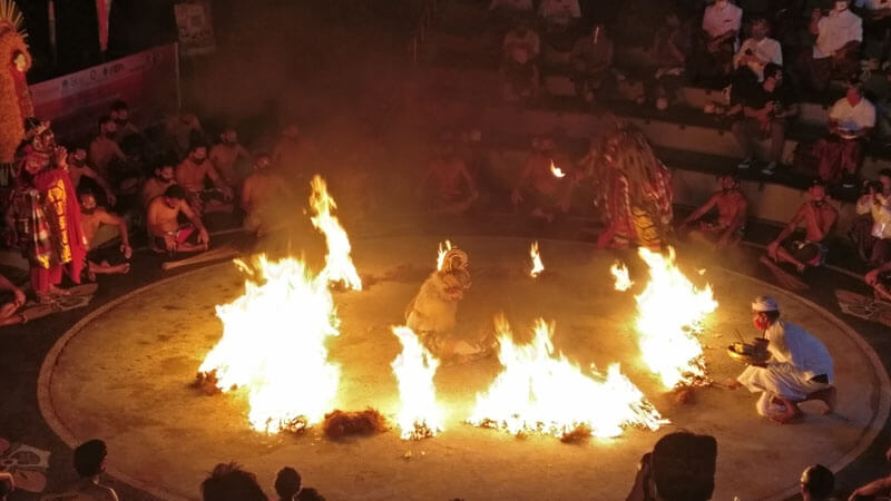 Penampilan Tari Kecak di malam hari dengan lingkaran api yang menyala, sebagai bagian dari ritual kebudayaan di Pura Uluwatu, Bali.