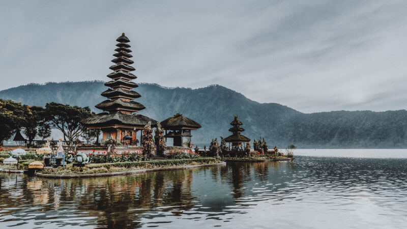 Pura Ulun Danu Beratan yang megah dengan latar belakang pegunungan Panorama Tirta Gangga dengan kolam ikan koi dan taman lanskap salah satu destinasi liburan unik di Bali.