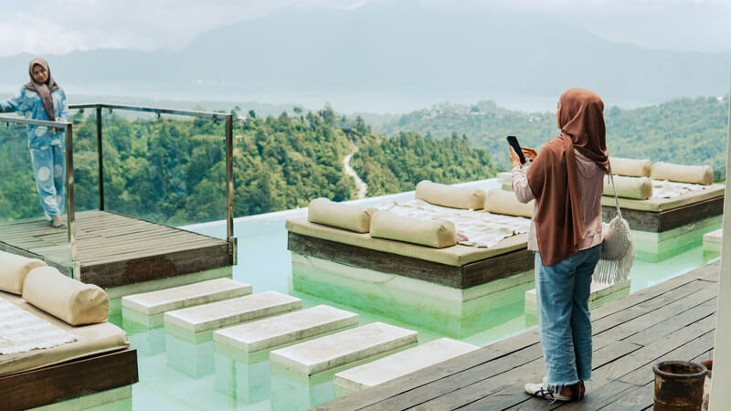 Turis menikmati pemandangan Kintamani dari dek dengan latar belakang pegunungan dan danau