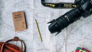 Peta perjalanan, kamera, dan buku catatan sebagai persiapan untuk itinerary liburan di Bali.