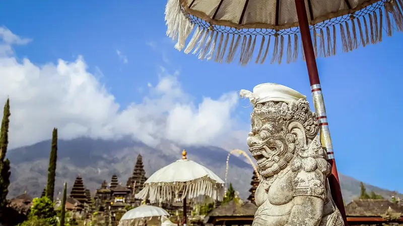 Patung penjaga di Pura Besakih dengan latar belakang Gunung Agung