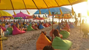 Payung warna-warni dan suasana santai di Pantai Seminyak saat sunset.