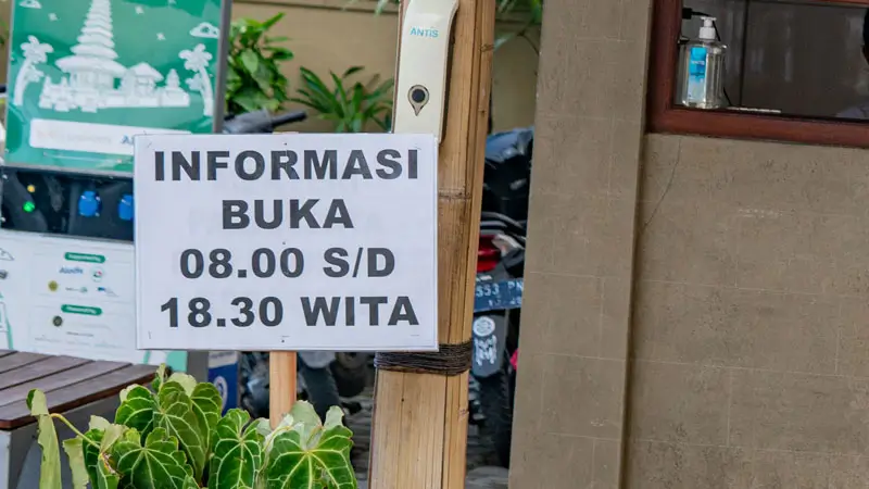 Papan jam operasional 08.00–18.30 WITA
