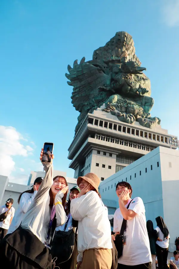 Keceriaan wisatawan di Garuda Wisnu Kencana Bali dengan latar patung ikonik. Foto © GWK