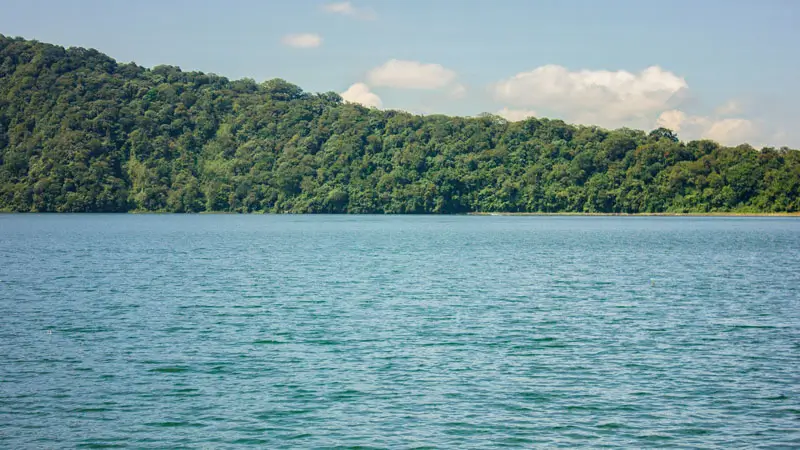 Danau tenang di Bedugul Bali dengan latar hutan hijau dan langit cerah