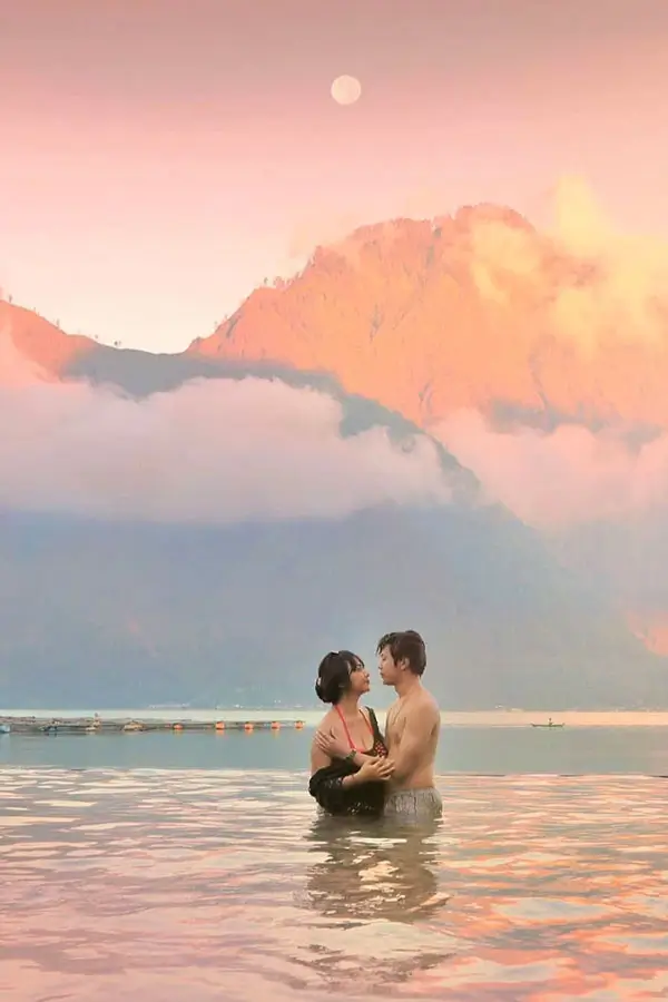Pasangan berendam di kolam air panas Kintamani dengan latar gunung
