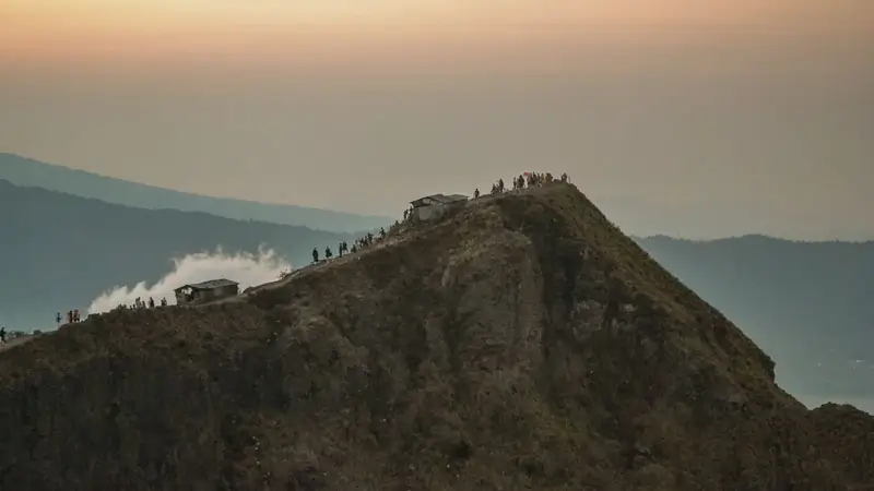 pendaki berkumpul di puncak Gunung Batur saat sunrise.