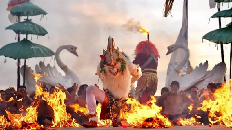 Hanoman di segmen api Tari Kecak Melasti, penari mengitari bara di panggung tepi laut.
