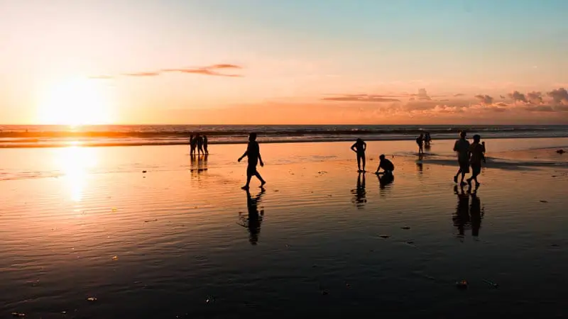 Sunset di Pantai Kuta dengan siluet pengunjung di pasir basah