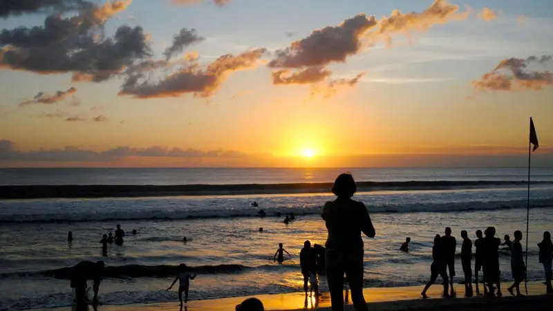 Sunset di Pantai Seminyak dengan siluet pengunjung dan garis pantai