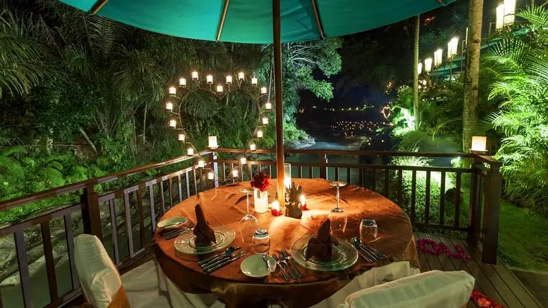 Makan malam romantis dengan cahaya lilin di tepi Sungai Ayung di Ubud untuk pasangan yang sedang berbulan madu.