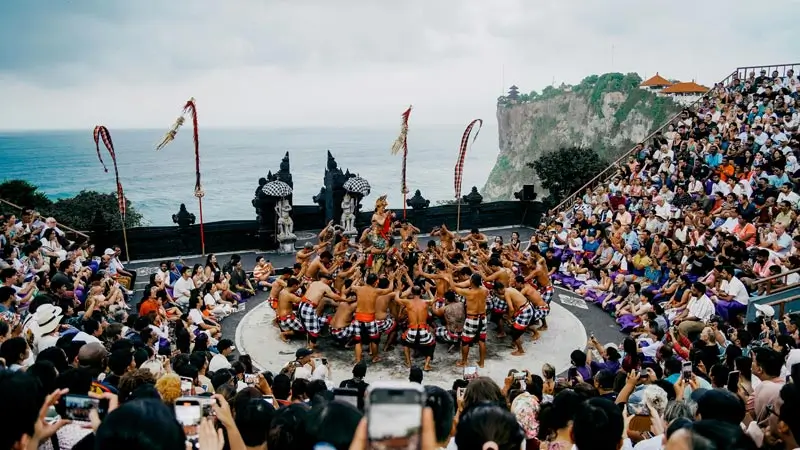 Panggung Kecak Uluwatu berlatar tebing dan laut; penari membentuk lingkar