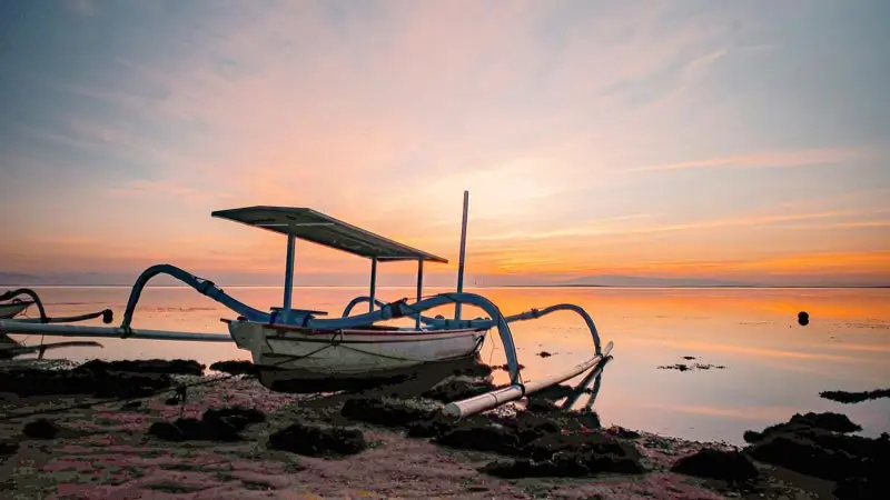 Perahu jukung tradisional di Pantai Matahari Terbit Sanur saat matahari terbit di atas laut tenang