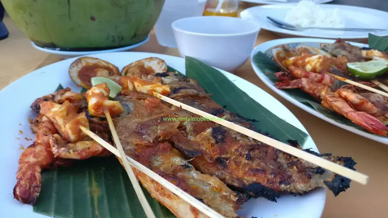 Seafood bakar khas Bali dengan ikan, udang, dan sate di cafe tepi Pantai Jimbaran saat Uluwatu Half Day Tour.