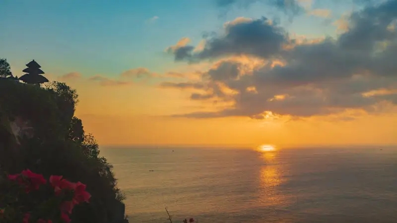 Sunset di Pura Uluwatu Bali dengan siluet pura di tebing menghadap laut