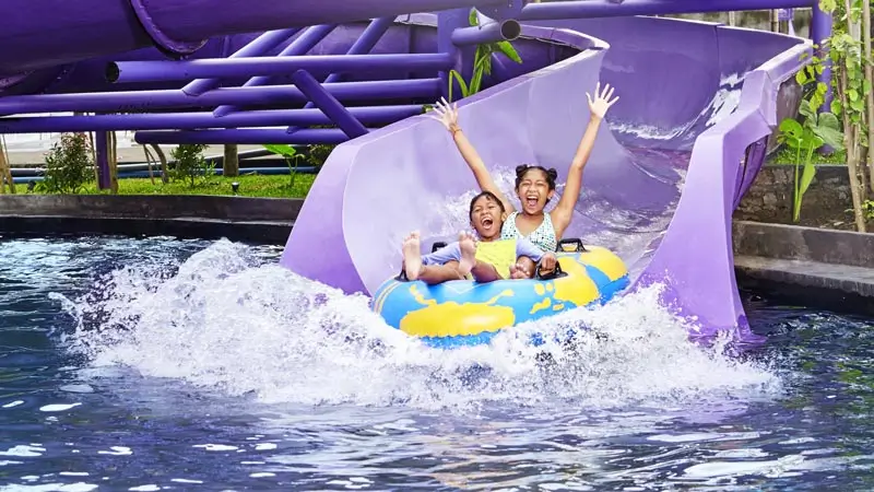 Anak bermain seluncuran air ungu di waterpark Kintamani