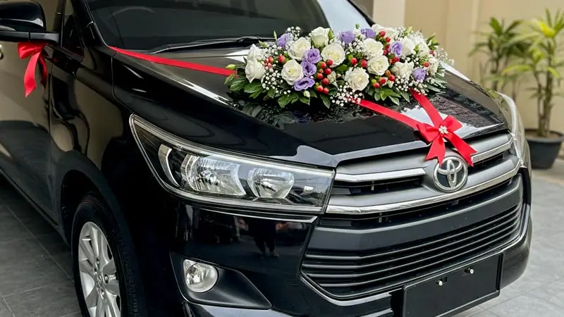 Innova Reborn mobil pengantin Bali dengan dekor bunga dan pita.