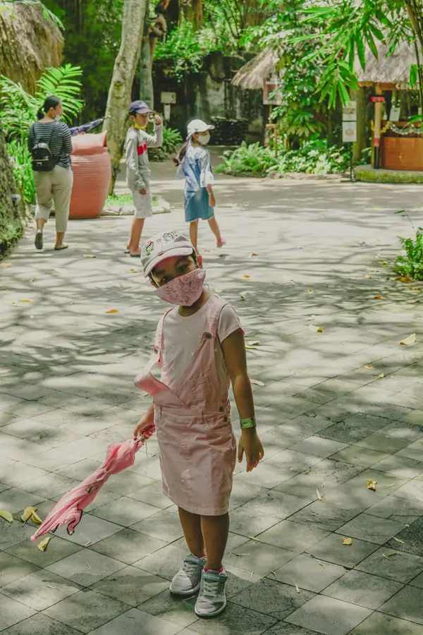 Pengunjung kecil berjalan di area teduh bersama keluarga
