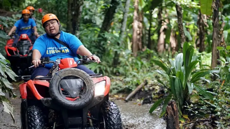 Peserta naik ATV melewati jalur berlumpur di area hijau